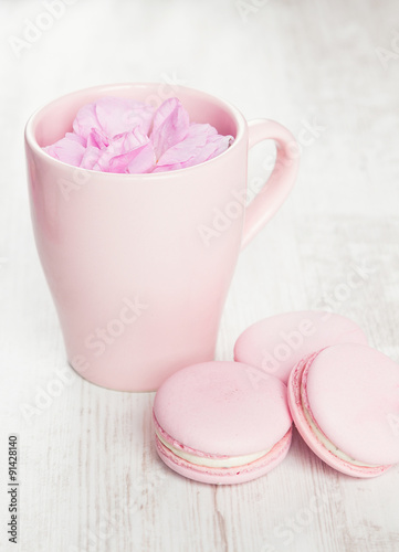 Tender pink macaroons and tea cup on white wood background