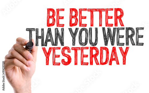 Hand with marker writing: Be Better Than You Were Yesterday photo