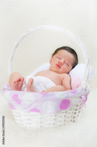 Bebé recién nacido niña relajada en calma dormida en una cesta blanca y rosa sobre una manta de pelo
