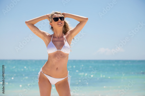 Woman in white bikini posing on the beach