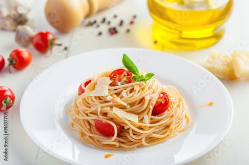 Italian spaghetti with tomato sauce, parmsesan cheese and basil on table