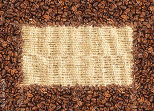 Spilled coffee beans frame over burlap textile