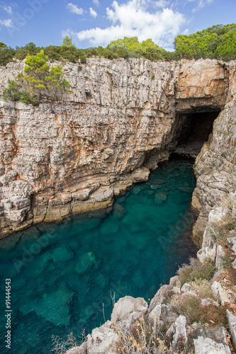 Empty sea cave, shallow water and steep and rugged cliff at the Lokrum Island in Croatia.