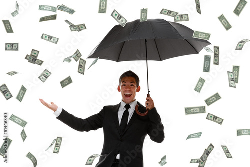 Excited businessman holding hand out in a money rain storm photo