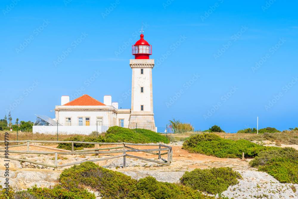 Lighthouse building on top of cliff on coast of Portugal near Carvoeiro town