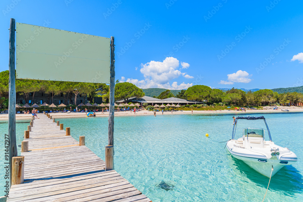 Wooden jetty on Santa Giulia beach with dinghy boat on azure sea, Corsica island, France Wooden jetty on Santa Giulia beach with dinghy boat on azure sea, Corsica island, France