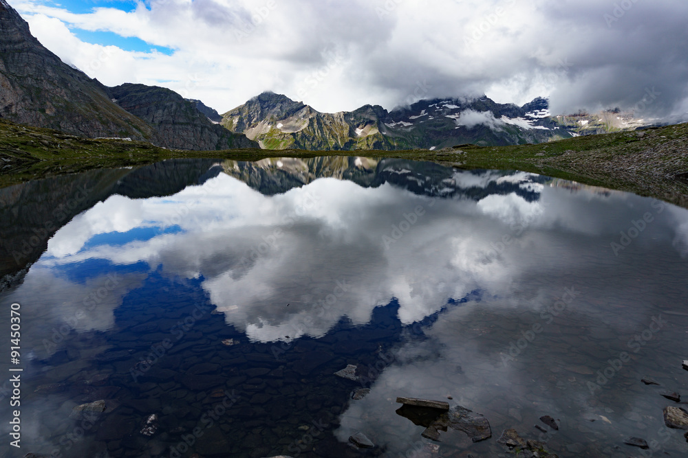 Bergsee mit sich spiegelnden Wolken