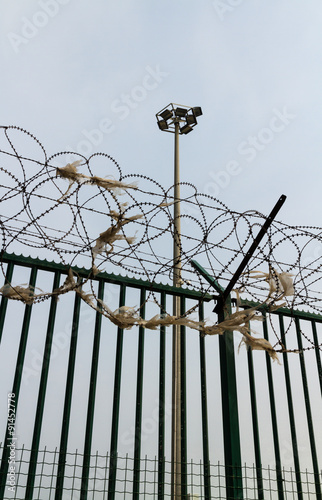 Green fence with razor wire and floodlights guarding French ferr photo