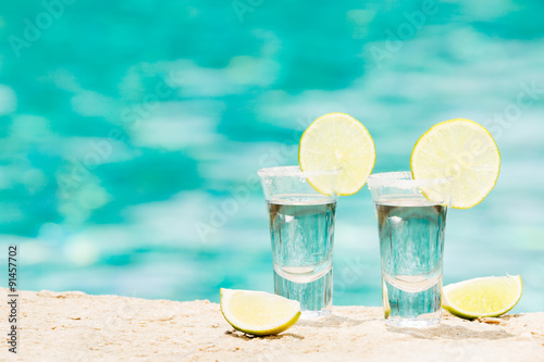 Tequila shots with lime on blue background