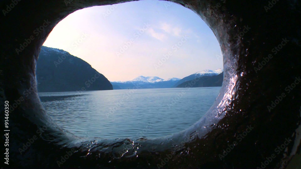 A view through the porthole of a ship crossing the fjords of Norway.