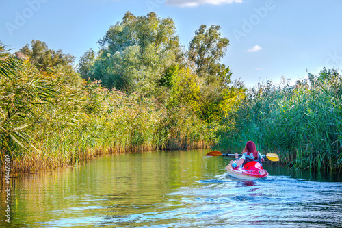Landscape image of red-haired girl in a canoe