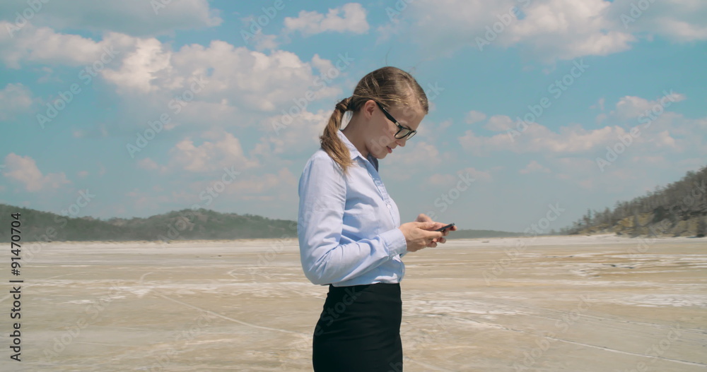 Desperate business woman vainly trying to make a phone call in desert Desperate business woman vainly trying to make a phone call in desert