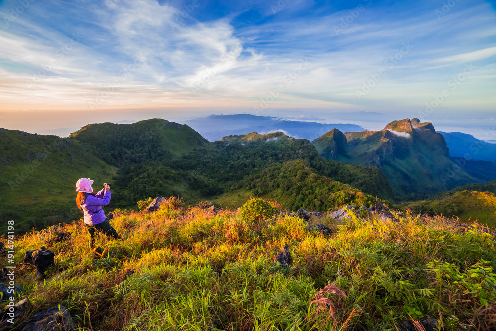 young woman take photographs during Sunset on mountain with landscape view