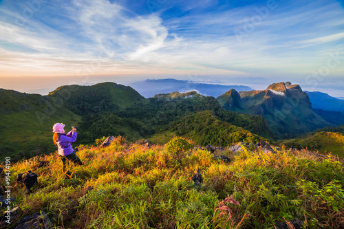young woman take photographs during Sunset on mountain with landscape view © khlongwangchao