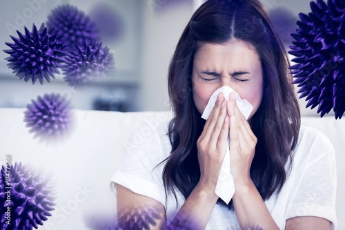 Wall Mural Composite image of brunette sneezing in a tissue