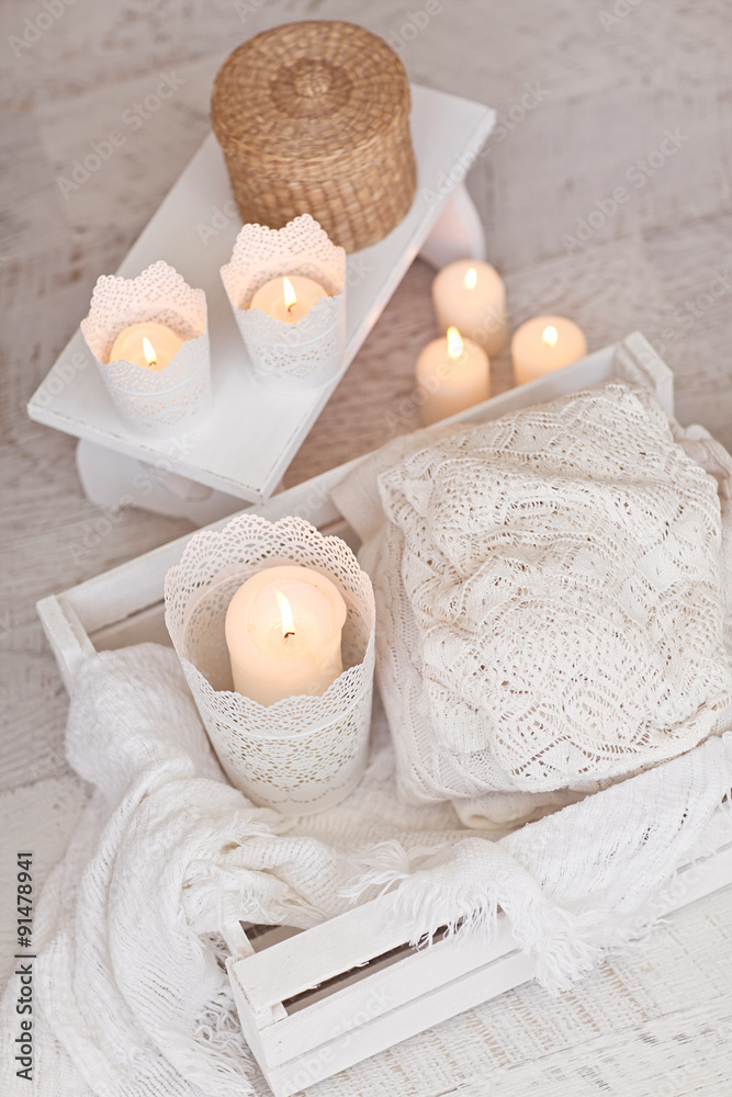 Warm white wool sweaters on white wood stool with candles and te Warm white wool sweaters on white wood stool with candles and te