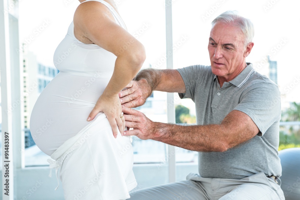 Obraz premium Therapist massaging back of pregnant woman