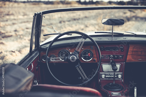 Steering wheel and dashboard in interior of old automobile.