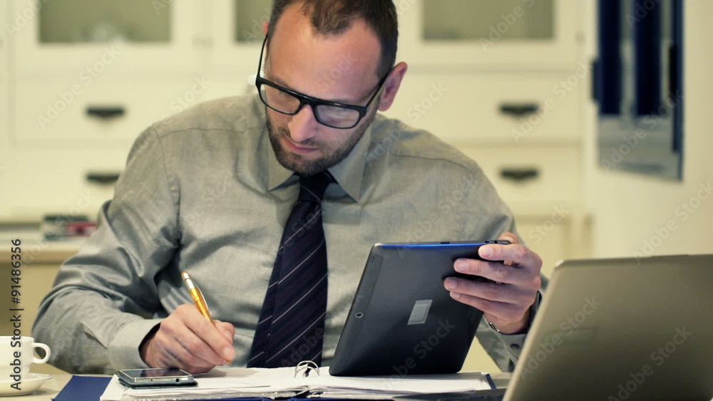 Busy businessman working at night sitting by table in kitchen
Busy businessman working at night sitting by table in kitchen