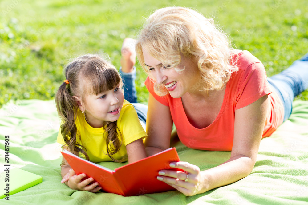 Mother with daughter in park reading book Mother with daughter in park reading book