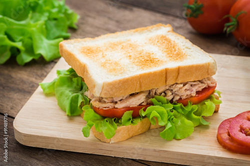 Tuna sandwich with vegetables on wooden plate