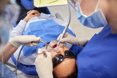 female dentist treating male patient teeth