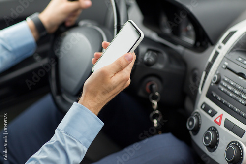 close up of man hand with smartphone driving car