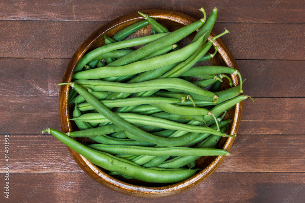 Green beans in wooden plate, close up Green beans in wooden plate, close up