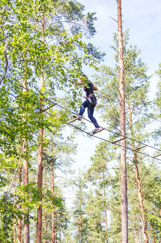 Young brave woman climbing in a adventure rope park