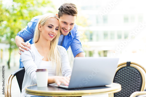 Couple using laptop at cafe