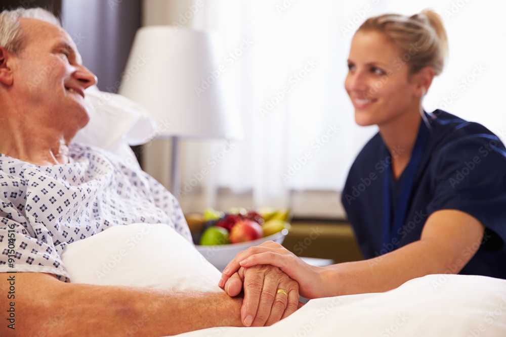 Nurse Talking To Senior Male Patient In Hospital Bed Nurse Talking To Senior Male Patient In Hospital Bed