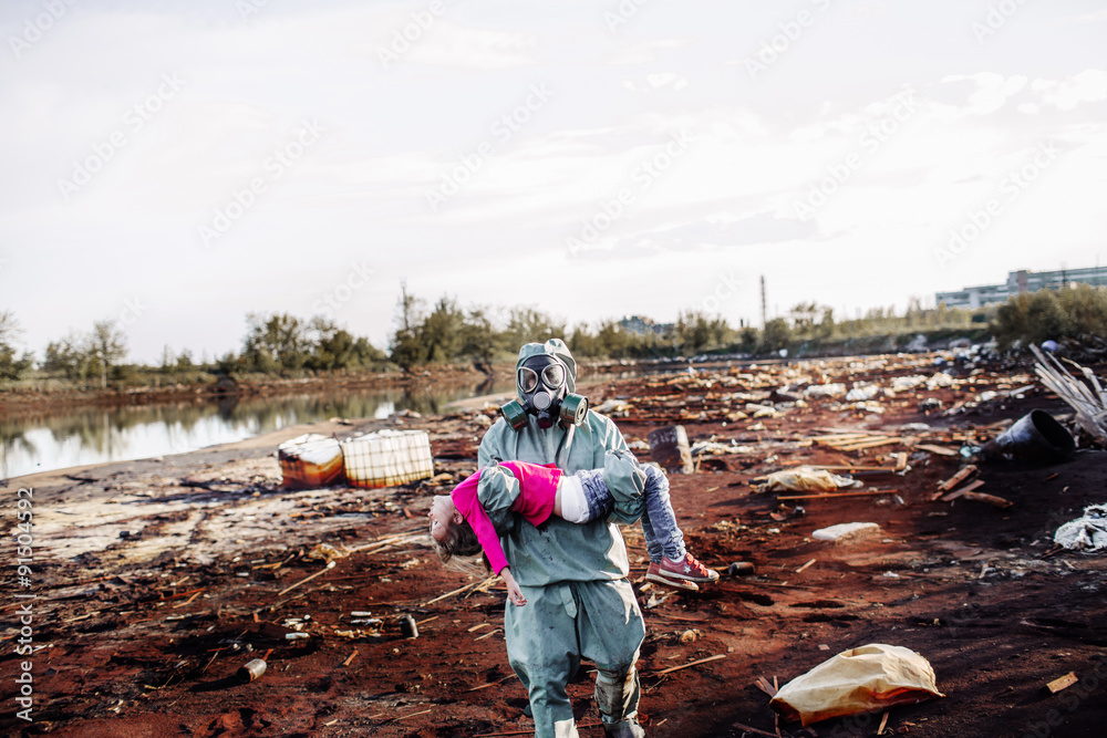 Man carries a child on the background of ecological disaster
