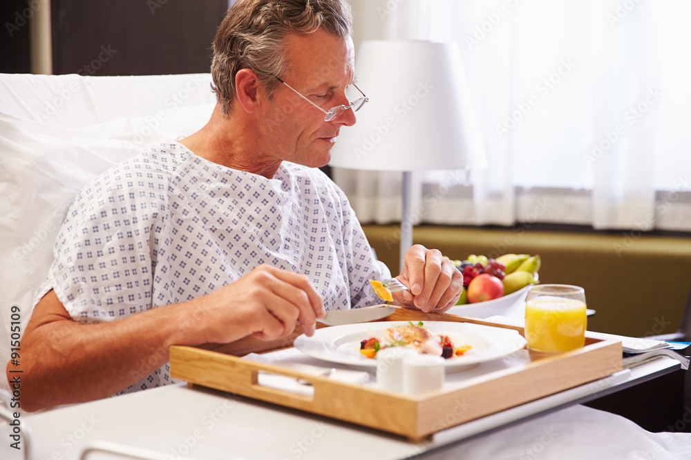 Male Patient In Hospital Bed Eating Meal From Tray Male Patient In Hospital Bed Eating Meal From Tray