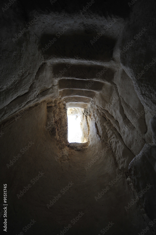 Underground narrow passage with stairs leading up to the light 