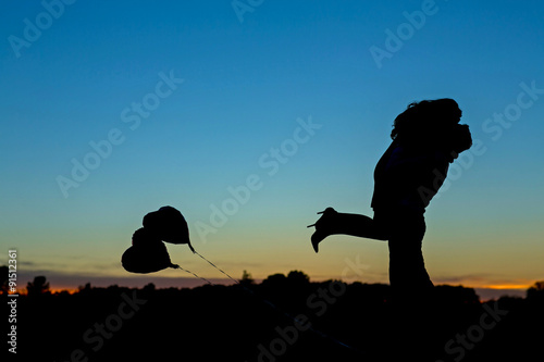 Passionate silhouette of an engaged couple kissing with a beautiful sky sunset, she said yes