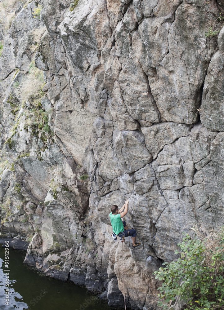 A man climbs on the rock near the water. A man climbs on the rock near the water.