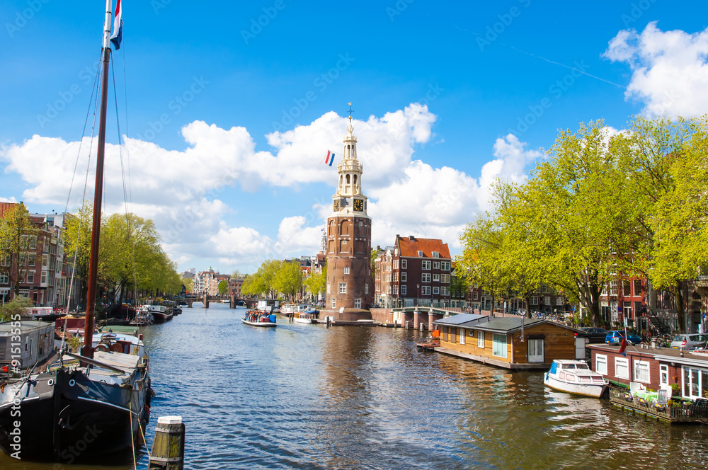 Panorama of Amsterdam with the Montelbaanstoren tower and houseboats along the bank of the canal Oudeschans, the Netherlands.
