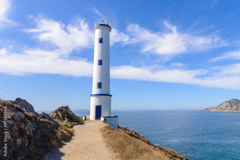 Lighthouse on the ocean against a blue sky