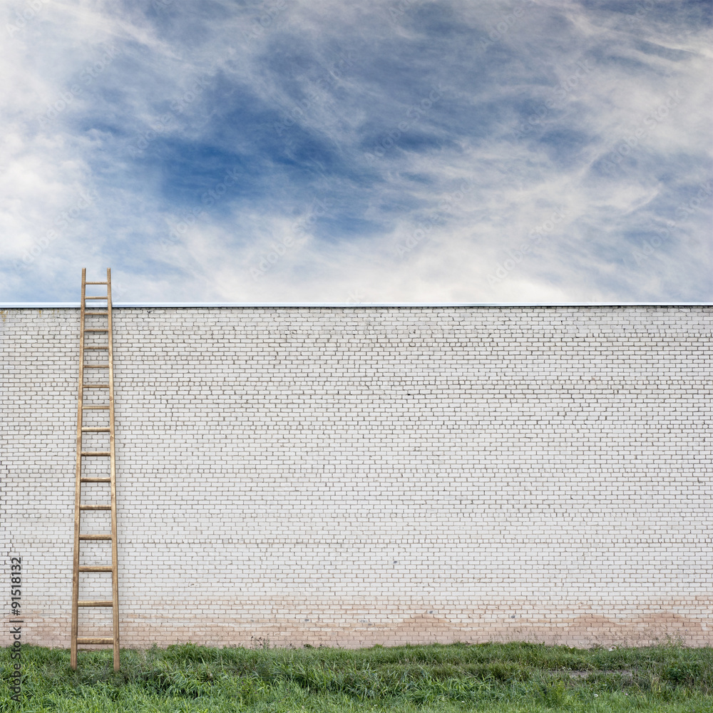 Fototapeta premium Blue sky behind the huge wall with a wooden ladder