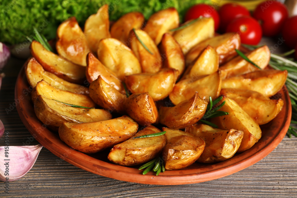 Baked potato wedges on wooden table, closeup Baked potato wedges on wooden table, closeup