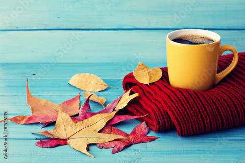 Coffee cup, red scarf and autumn leafs over turquoise wood