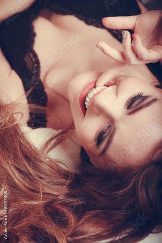 Portrait of happy young woman in lingerie in bed.