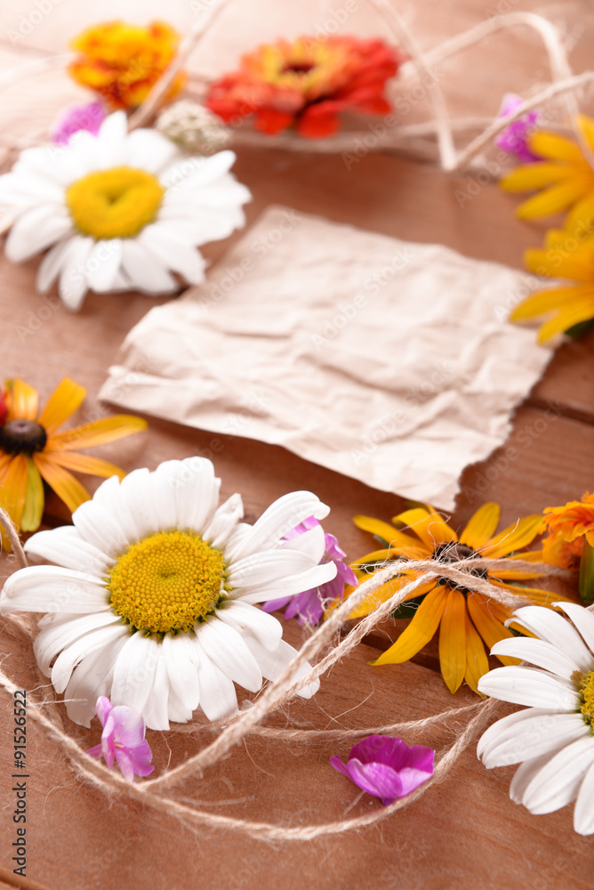 Fresh colorful flowers with crumpled sheet of paper on wooden table, closeup Fresh colorful flowers with crumpled sheet of paper on wooden table, closeup