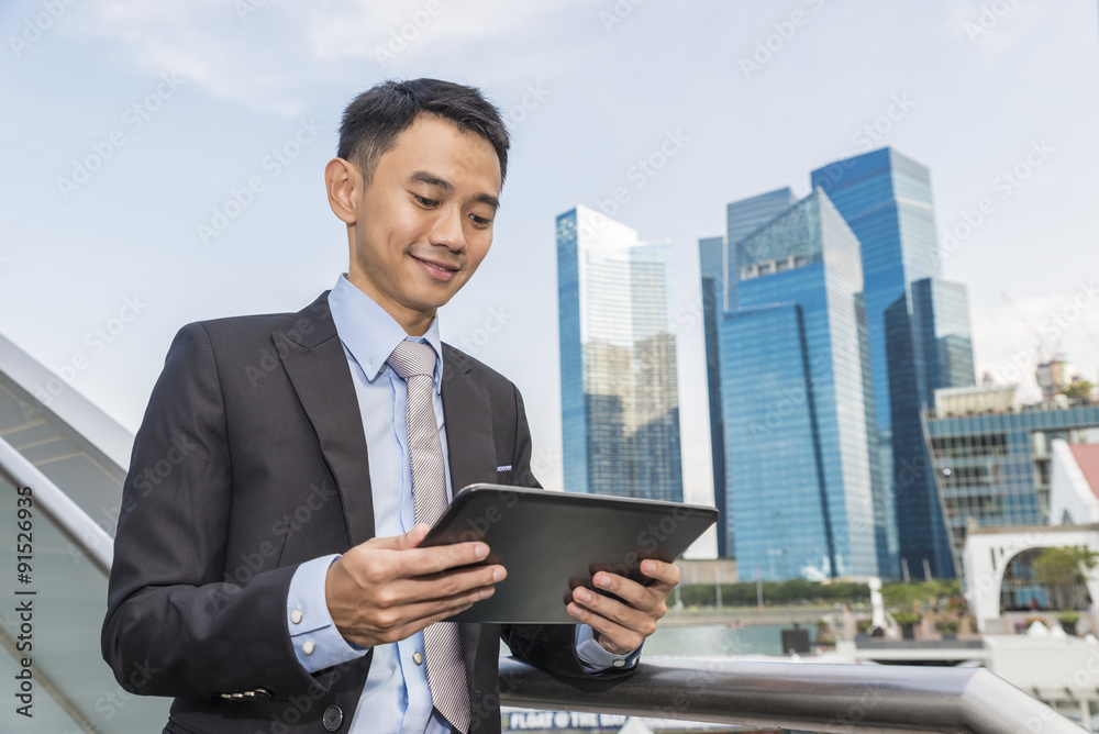 Asian business male using portable computer on city Asian business male using portable computer on city