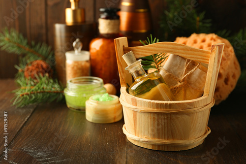 Essential oil of pine, handmade soap in wooden bucket and spa treatments on wooden background