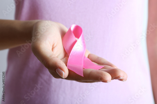 Pink ribbon in woman's hands close up