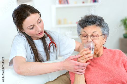 Giving senior woman a drink of water