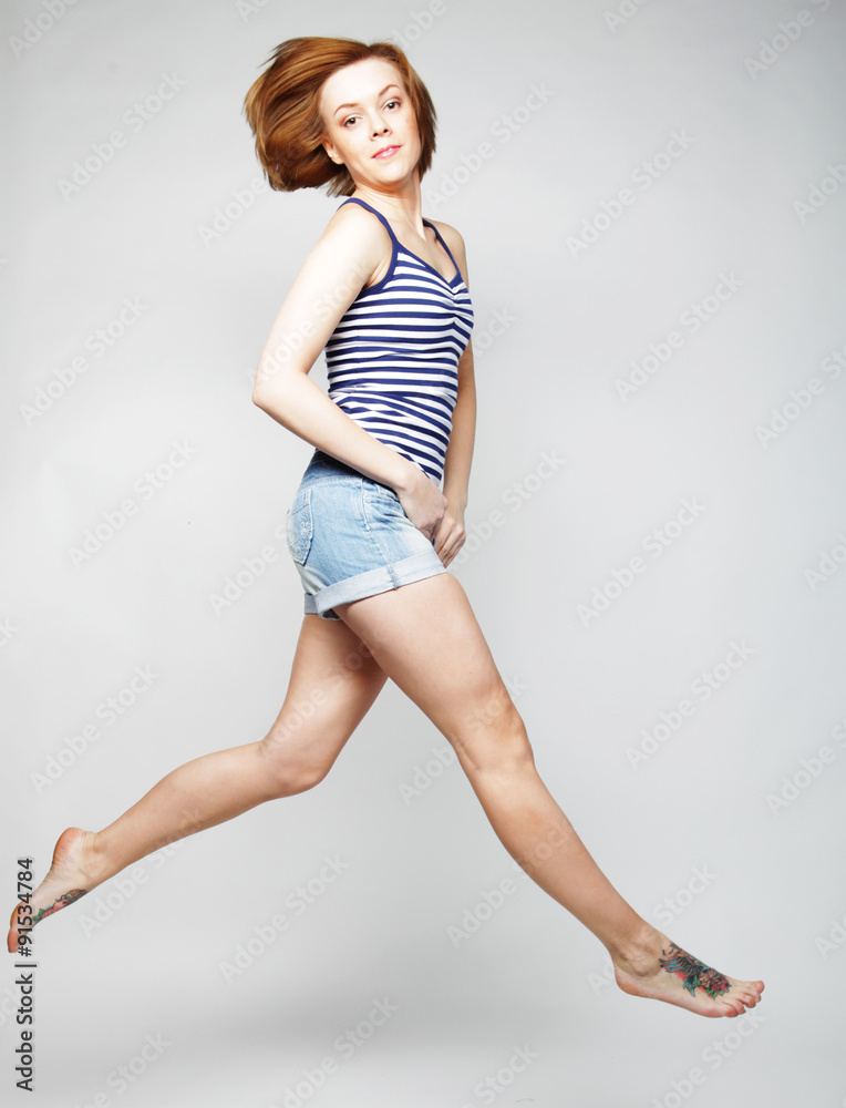 young lady jumping in joy over grey  background