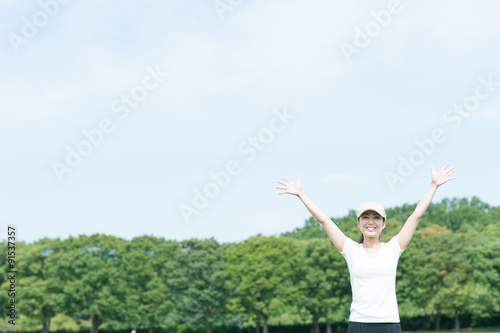 芝生の上で手を広げている女性