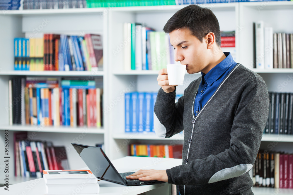 Student learning in library, drinking coffee. Student learning in library, drinking coffee.